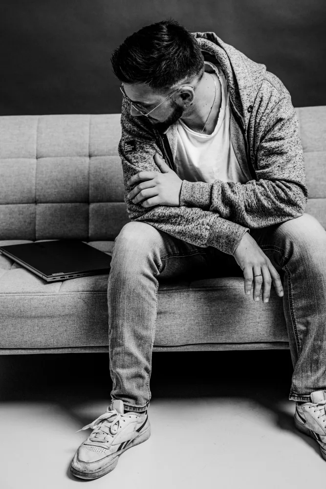 Schwarz-Weiß-Foto von Markus Pöschl, wie er auf einem Sofa sitzt